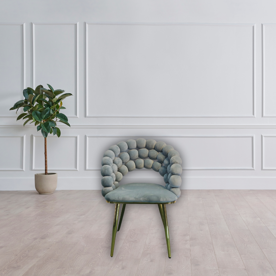 Grey bar stool. With round ball pattern top and gold square bottom platform, with gold legs and a square gold leg rest between legs